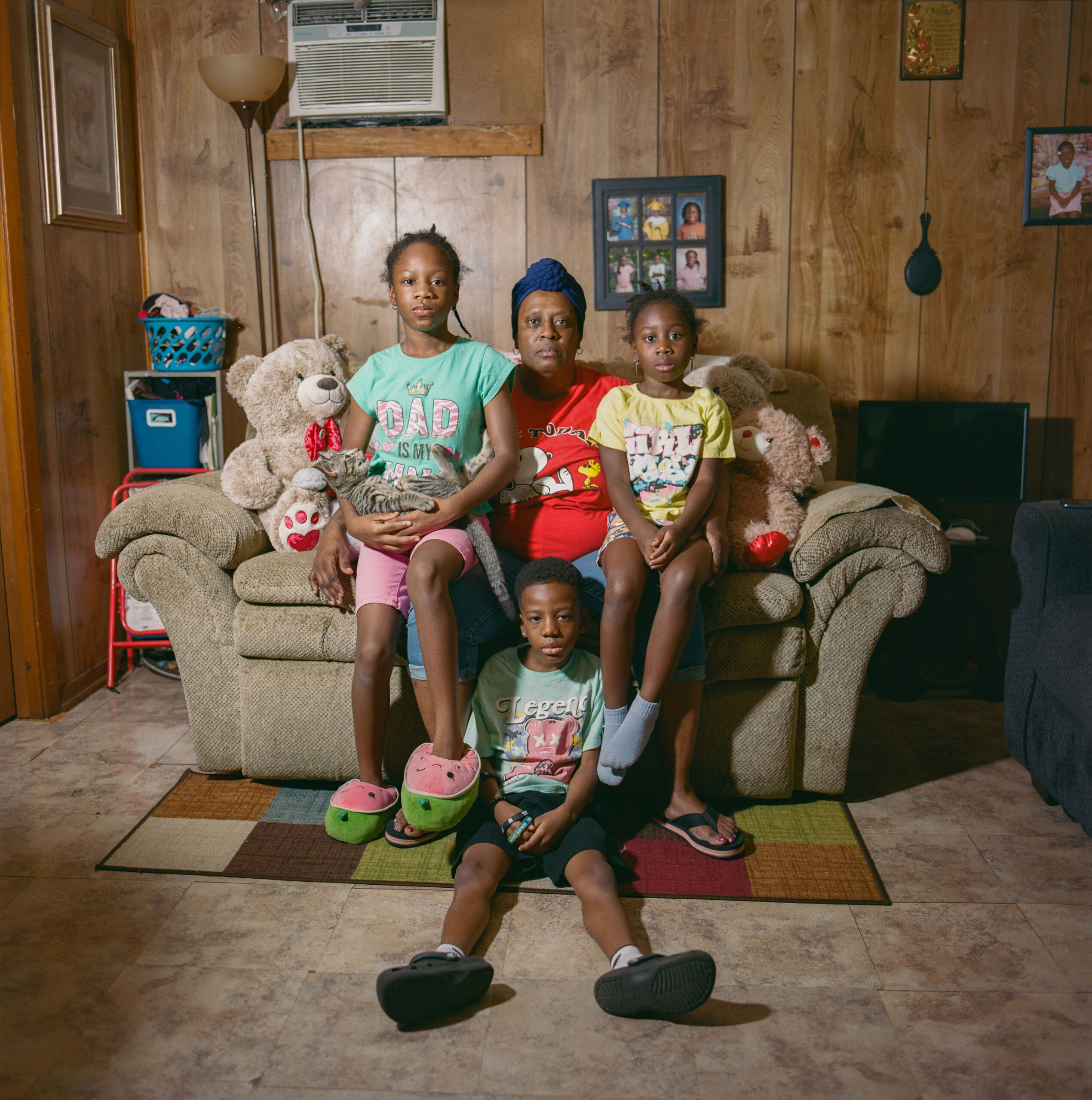Christie Harvey, 53, with her grandchildren—Leslie, 8 (left), Landon, 7 (middle), and Lacey, 6 (right)—face worsening respiratory issues since moving to Gloster four years ago. Christie uses a CPAP and breathing machine for asthma, and all three children have asthma and frequent sniffles. Leslie developed a respiratory disease at 7, and Landon manages ADHD and autism. Poor air quality and aging homes keep the family mostly indoors, with windows closed against dust and pollution.