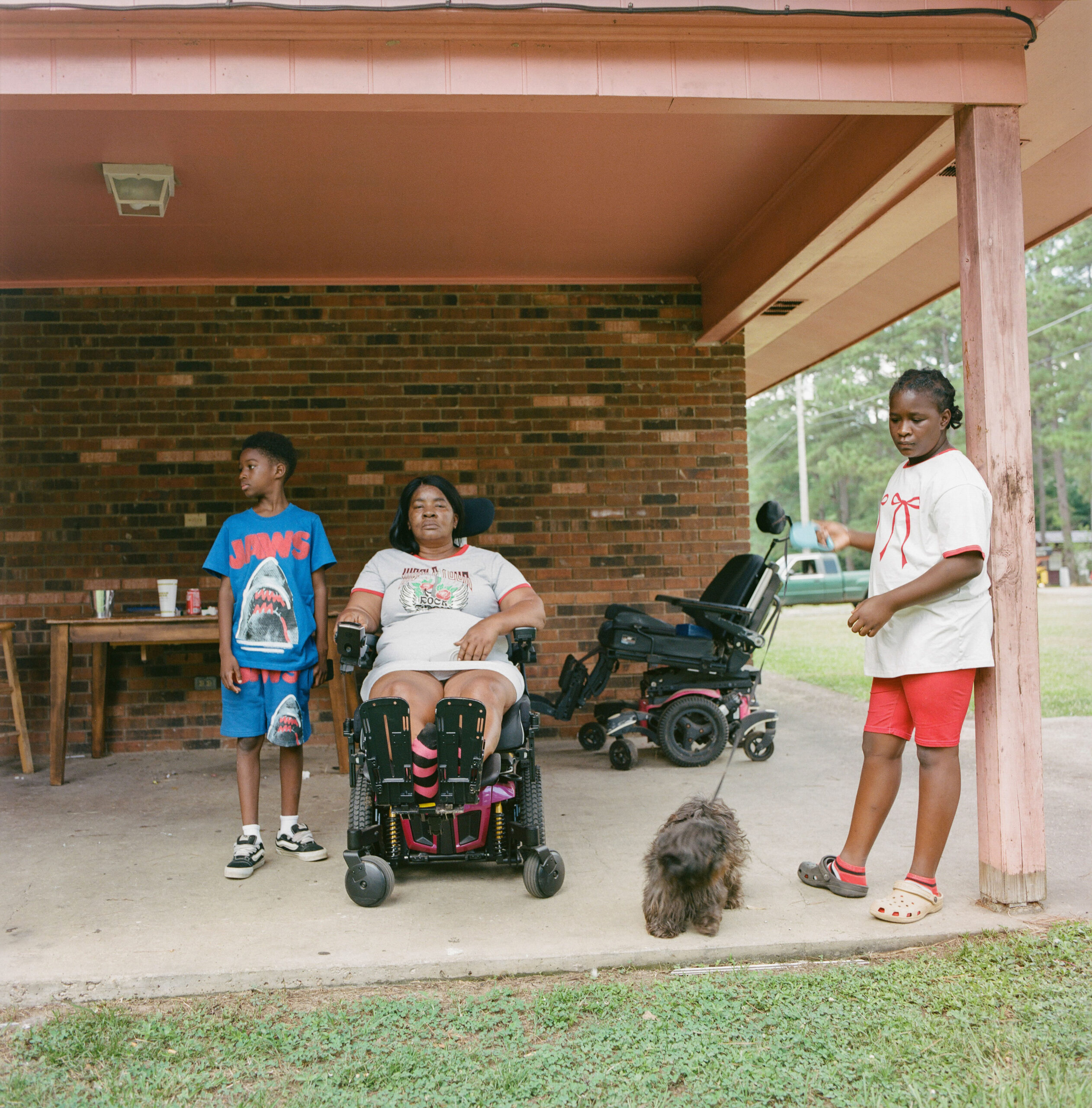Juanita Jackson, 59, a former truck driver, has battled multiple illnesses since 2019, including dizziness, balance issues, and asthma. She says, “The atmosphere was clear enough for us to breathe before Drax started operating here. I don’t even want to come outside now—I don’t know what’s getting into our systems.” Unable to open her windows due to heavy dust, she watches neighbors from her wheelchair each morning for a brief moment of sunlight and fresh air, with her daughter caring for her.