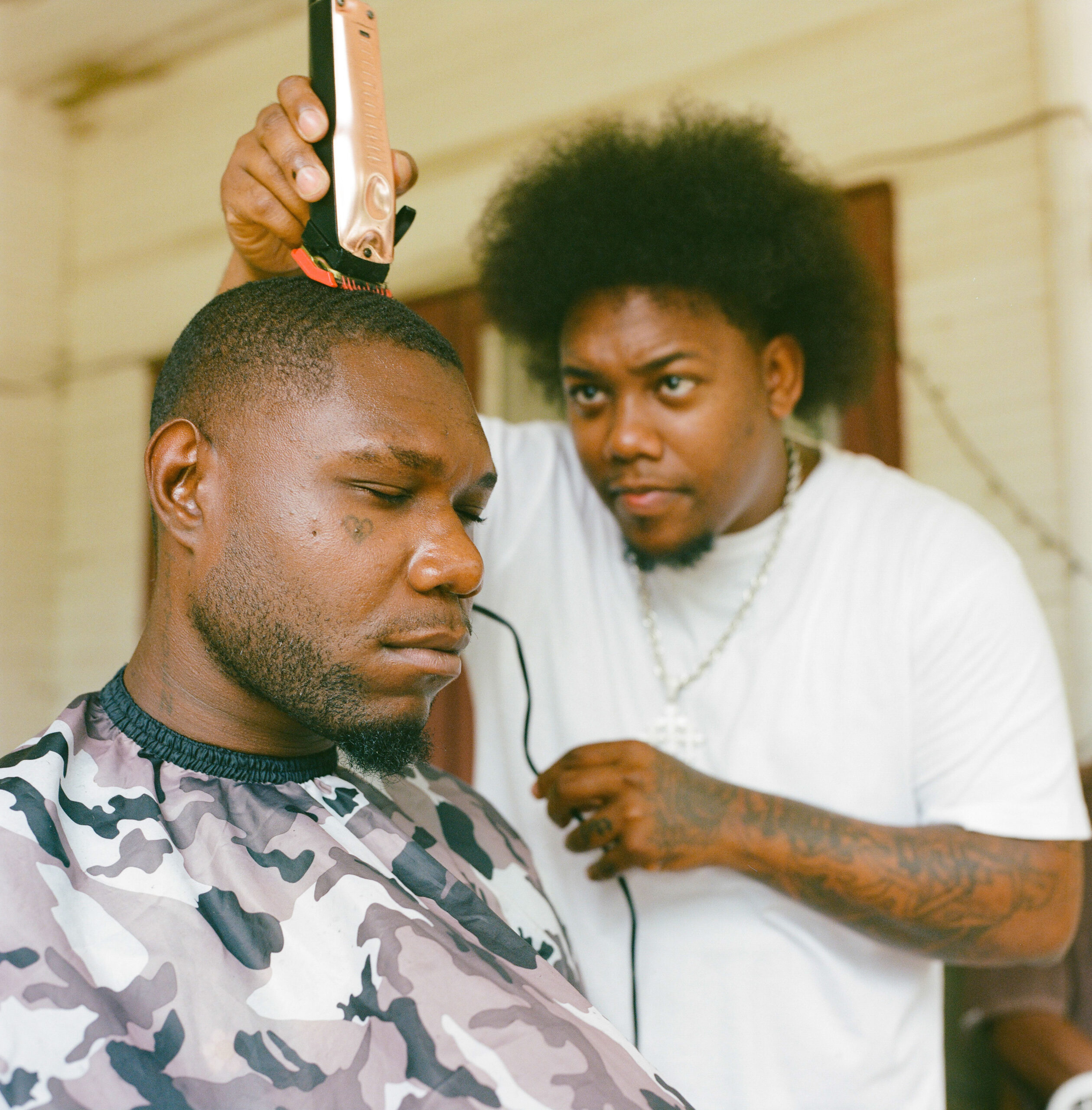 Kwame Bonds shaves his friend on the balcony.