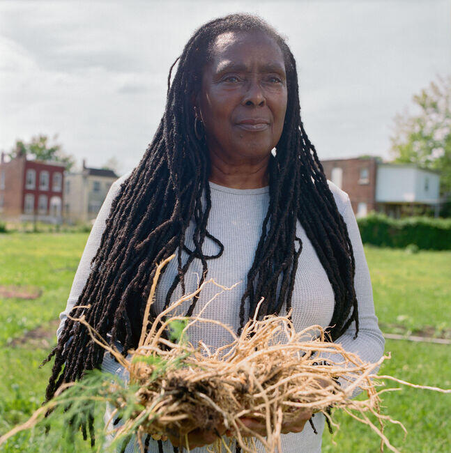 Pamela Talley visiting her friend Russell Houston’s community garden and holding the dead roots.