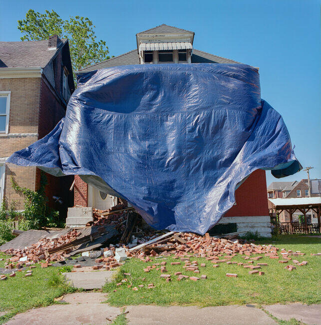 A house covered in tarps and debris stands damaged by the recent tornado. Next door is the home of William L. Jenkins. The two properties once shared a garden, a space that recently became the site of a community dinner, where neighbors gathered amid the wreckage to share food and solidarity.