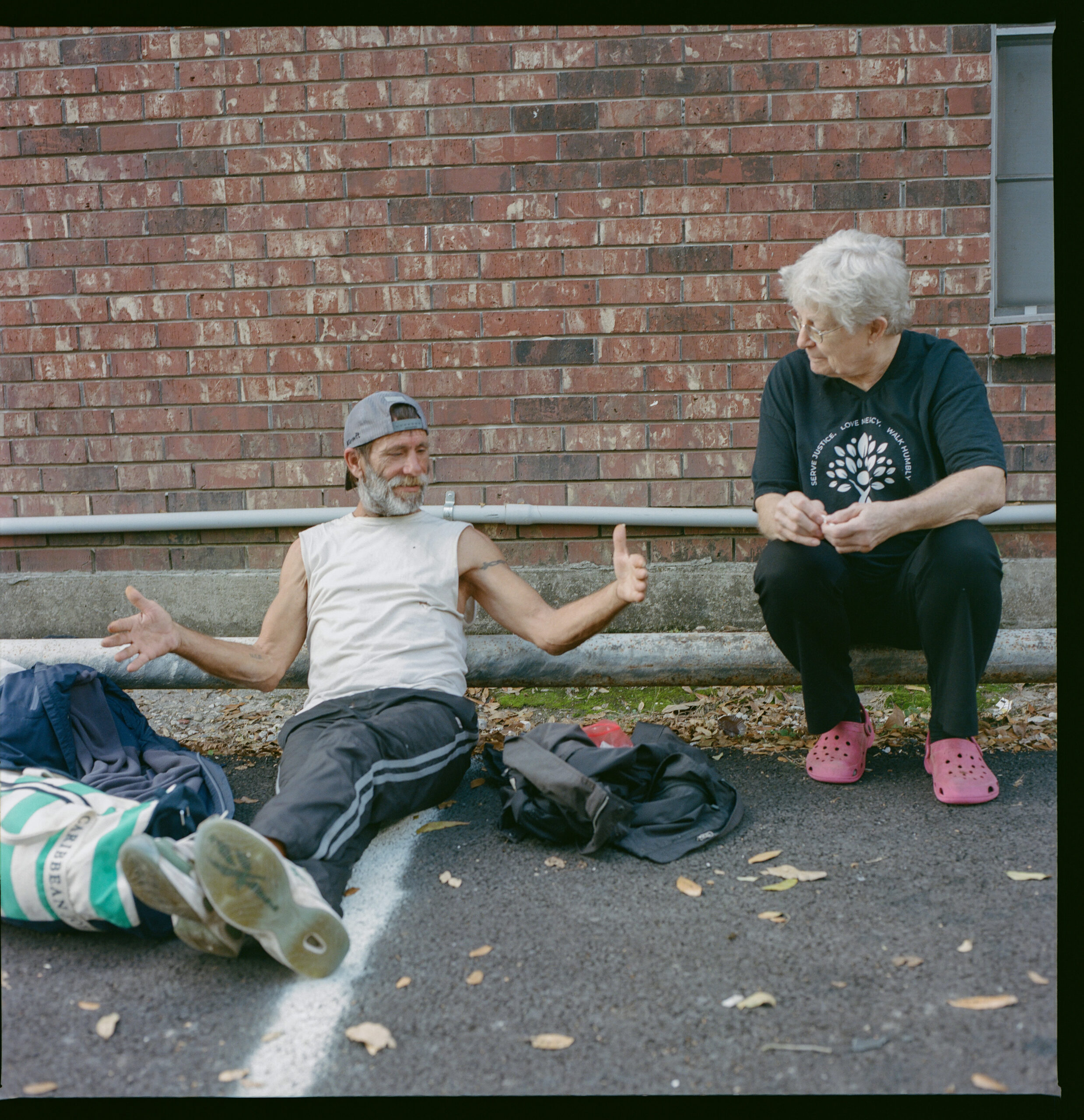 Cindy Robertson talks with Ronnie, an unhoused local, as he waits for free lunch at noon on the side of Sulphur Tabernacle Church.