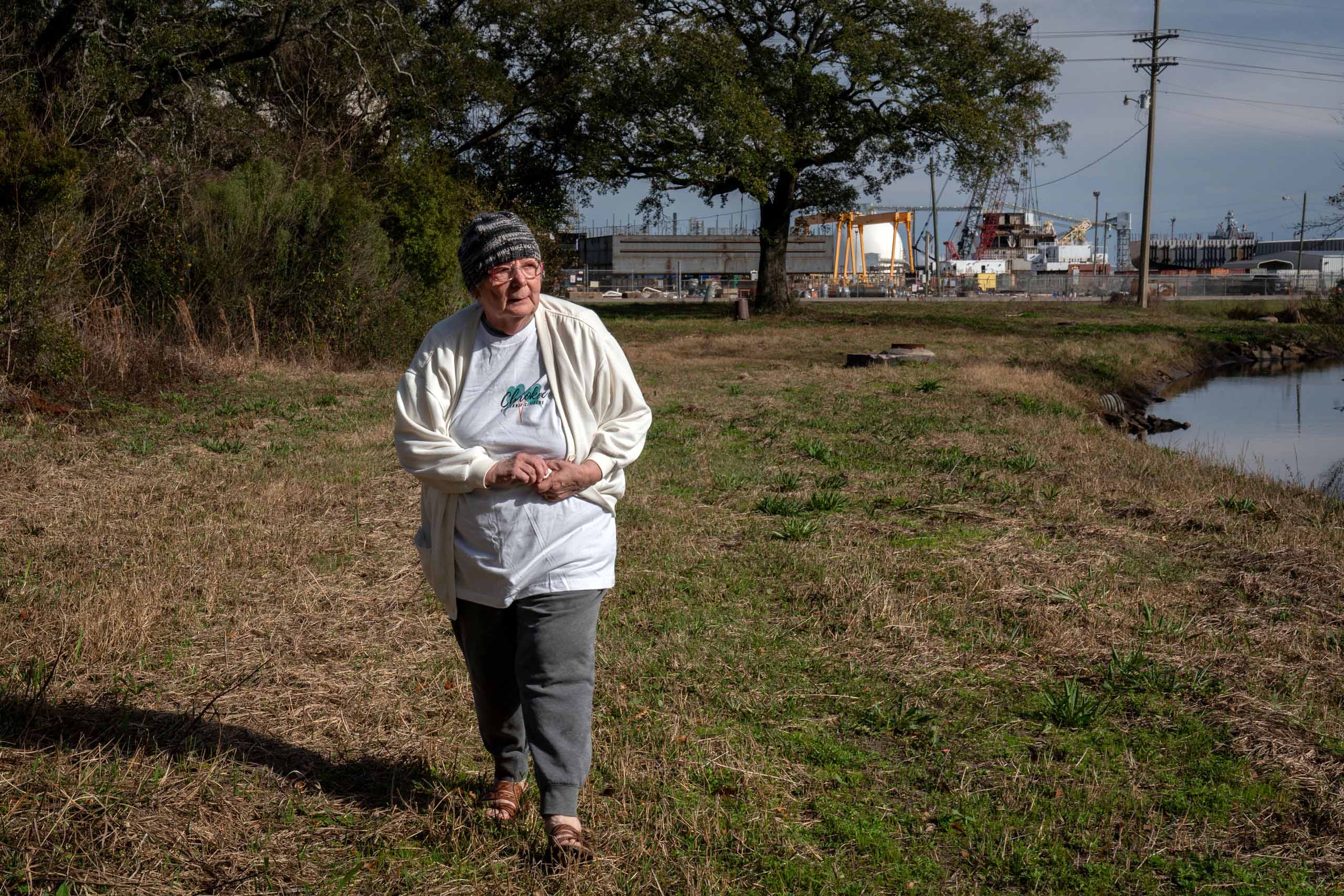 Barbara Weckesser, leader of Cherokee Concerned Citizens, walks near the large industrial facilities behind her home.